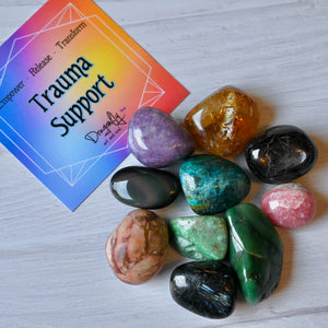 Colorful crystals on a white surface with a 'Trauma Support' card in the background.