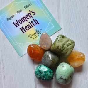 Colorful stones on a white surface with a 'Women's Health' card in the background.
