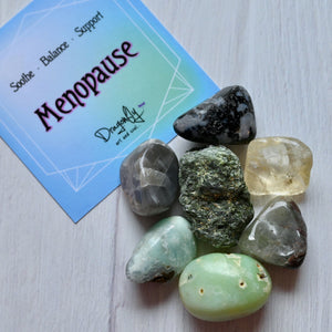 Collection of stones with a card labeled 'Menopause' on a light wooden surface