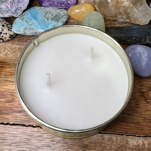 candle in a tin on wood surface with rocks in background