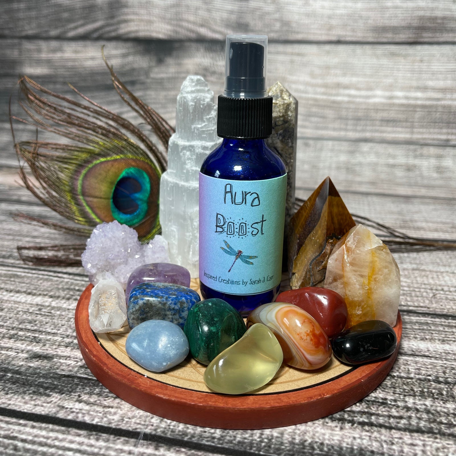 A group of nine Dragonfly Essential Oil Sprays featuring custom blends with various labels are arranged together. Names on the labels include "Florida Water," "Chill," "Earth Grounding Spray," and more. Each bottle has a black spray nozzle, perfect for all your mists and sprays needs. They are set on a wooden surface.
