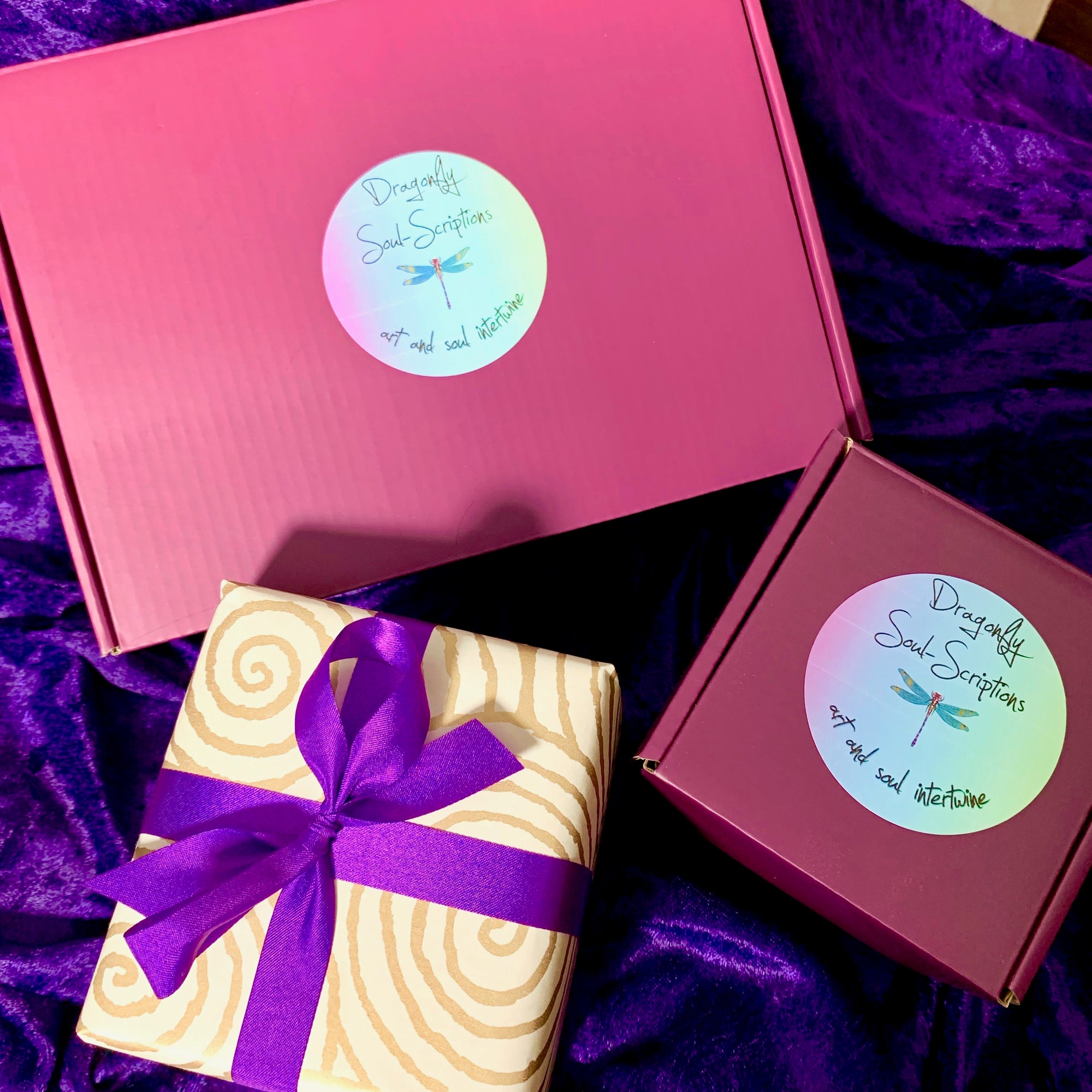 A purple Mystery Box labeled with a decorative design around the text. The label reads: "There are no wrong choices... Choose the one that speaks to your soul." Several other purple Mystery Boxes, each potentially hiding crystals or candles, are visible in the background.
