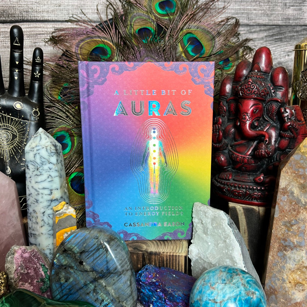 A book titled 'A Little Bit of Auras' by Cassandra Eason is displayed alongside various spiritual items.