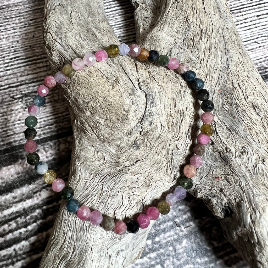 A multicolored tourmaline bracelet displayed on a wooden surface.